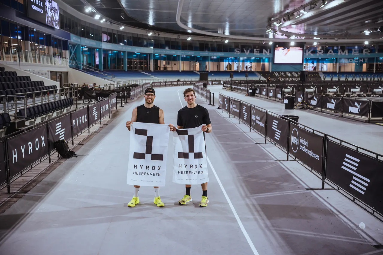 Maarten and his doubles partner holding first-place banners at Hyrox Thialf.